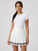 Woman wearing a white pleated mini skirt with black stripe hem in a studio setting