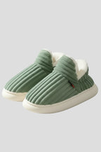 Woman wearing a green ribbed upper faux fur lined slipper - studio photo