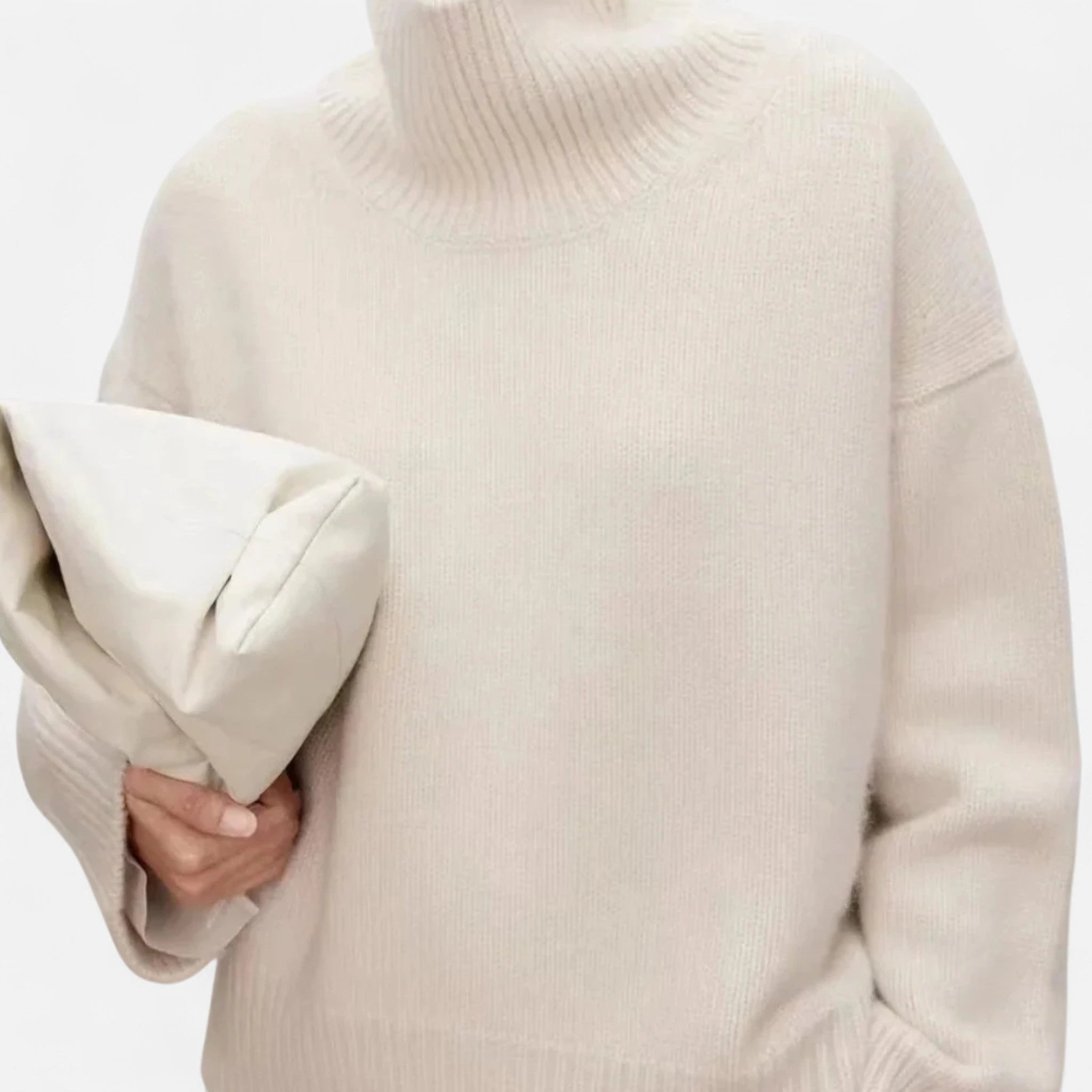 Woman wearing a beige oversized wool turtleneck sweater in a studio setting