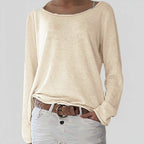 Woman wearing a beige lightweight boat neck sweater with relaxed draped fit