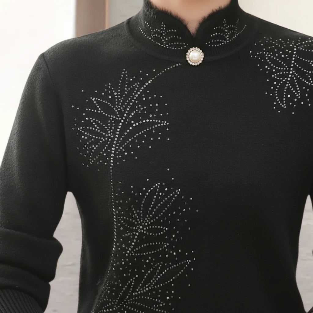 Close-up of black sweater high collar with pearl button and printed leaf pattern