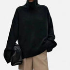 Woman wearing a black oversized wool turtleneck sweater in a studio setting