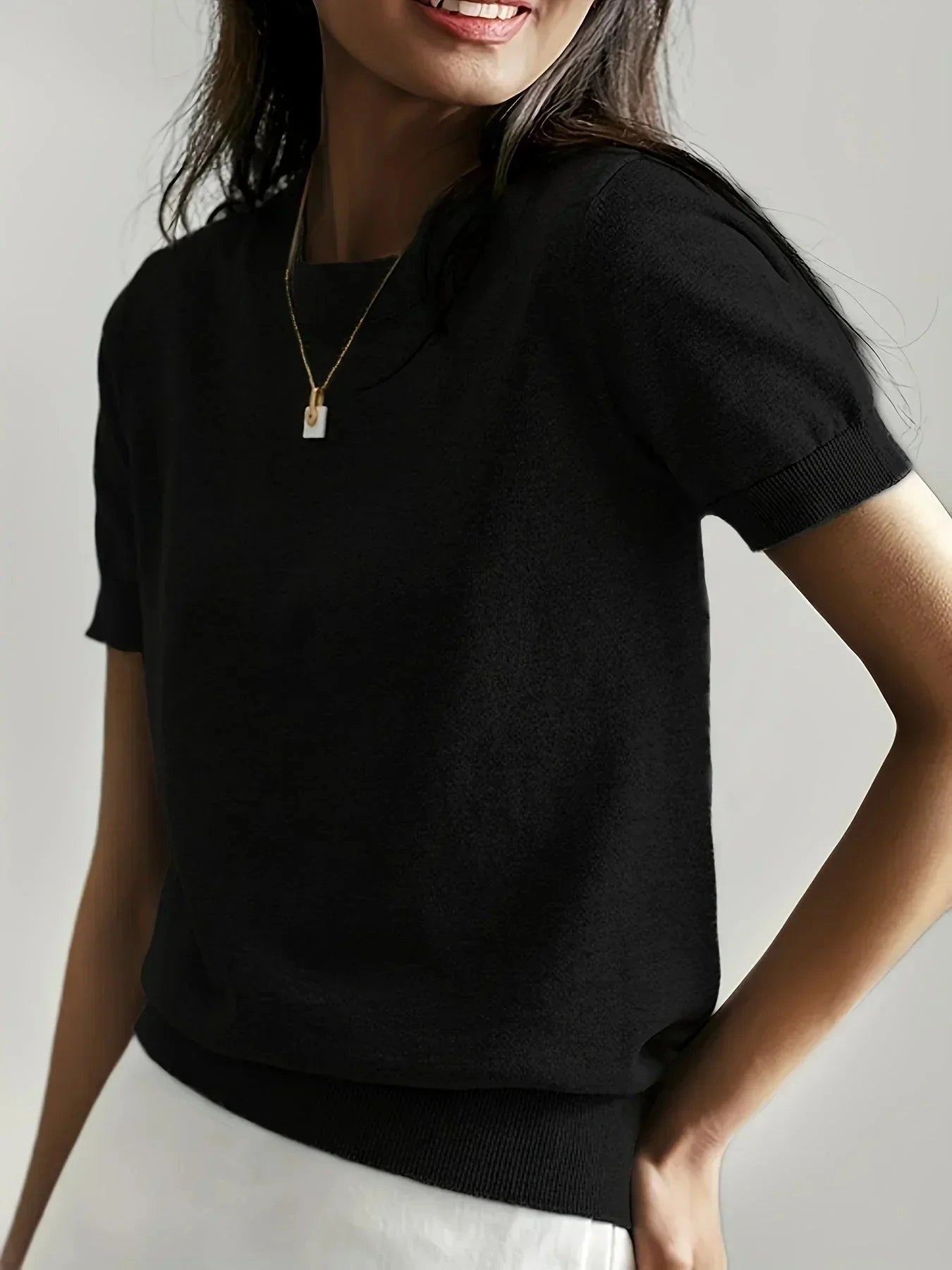 Woman wearing a black fine knit sweater with short sleeves and ribbed trim