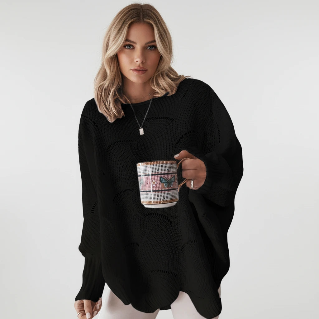 Woman wearing a black oversized open knit sweater with draped asymmetric hem, studio shot