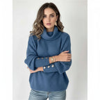 Woman wearing blue ribbed cowl neck sweater with button cuffs, studio photo
