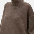 Woman wearing a brown oversized wool turtleneck sweater in a studio setting