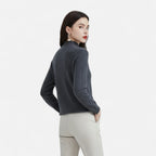 Woman wearing a dark grey wool half-neck sweater with beige trousers, back view