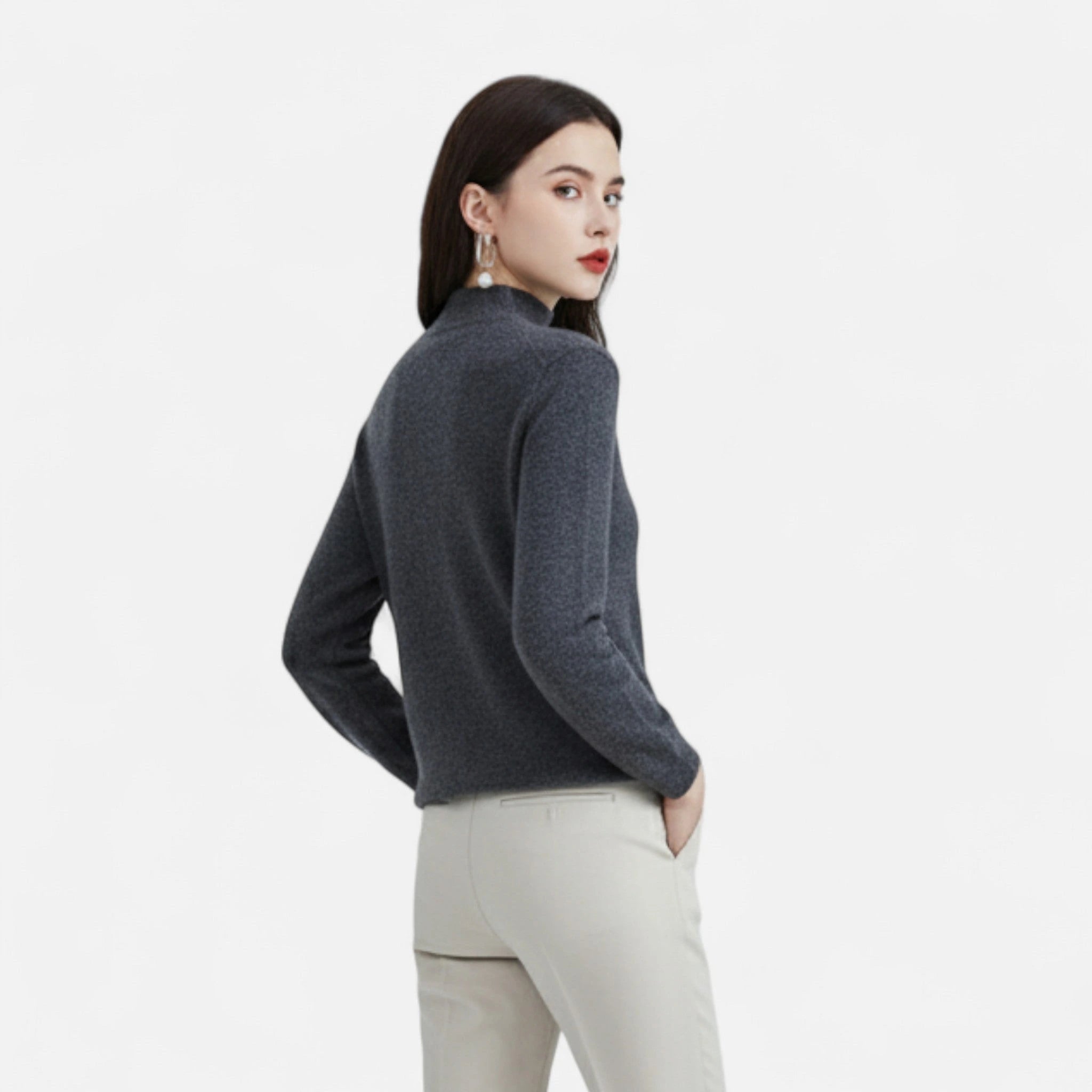 Woman wearing a dark grey wool half-neck sweater with beige trousers, back view