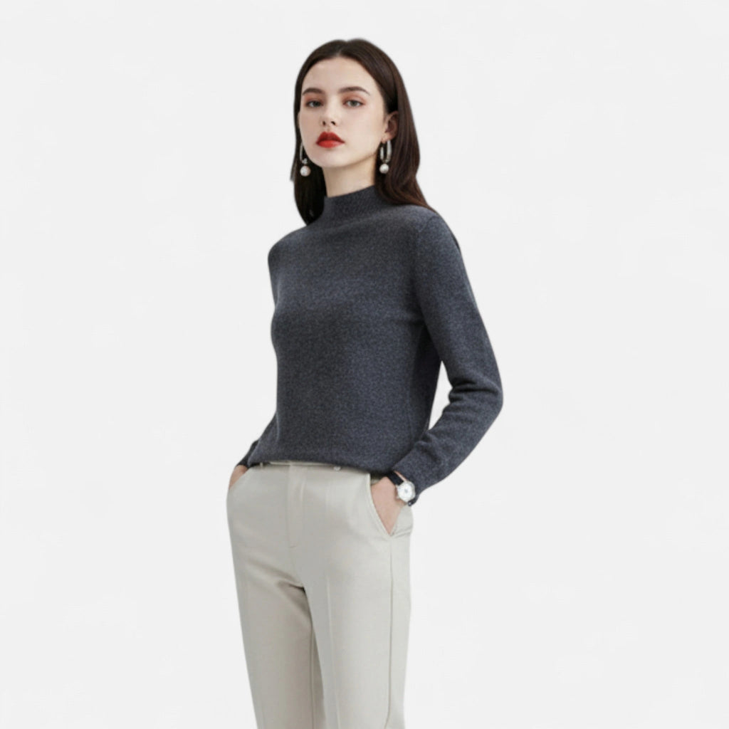Woman wearing a dark grey wool half-neck sweater with beige trousers, front view