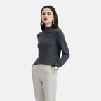 Woman wearing a dark grey wool half-neck sweater with beige trousers, front view