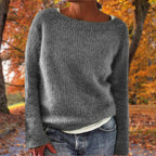 Woman wearing a grey merino wool sweater with an autumn background