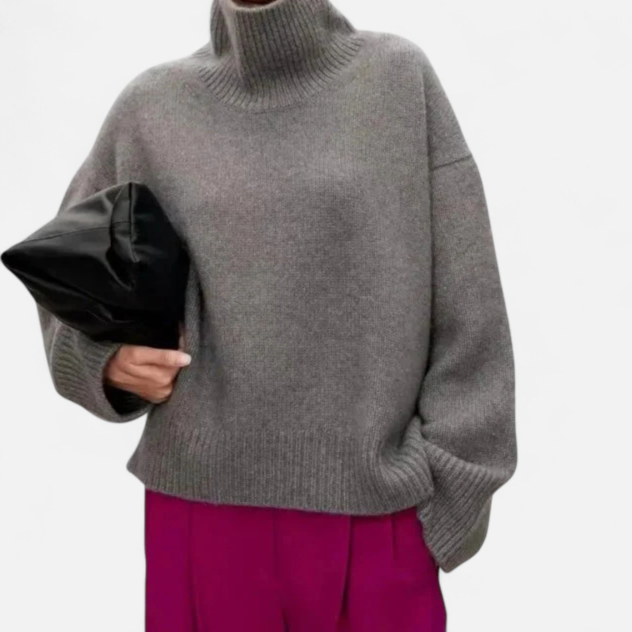 Woman wearing a grey oversized wool turtleneck sweater in a studio setting