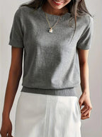 Woman wearing a grey fine knit sweater with short sleeves, side view