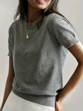 Woman wearing a grey fine knit sweater with short sleeves and ribbed trim
