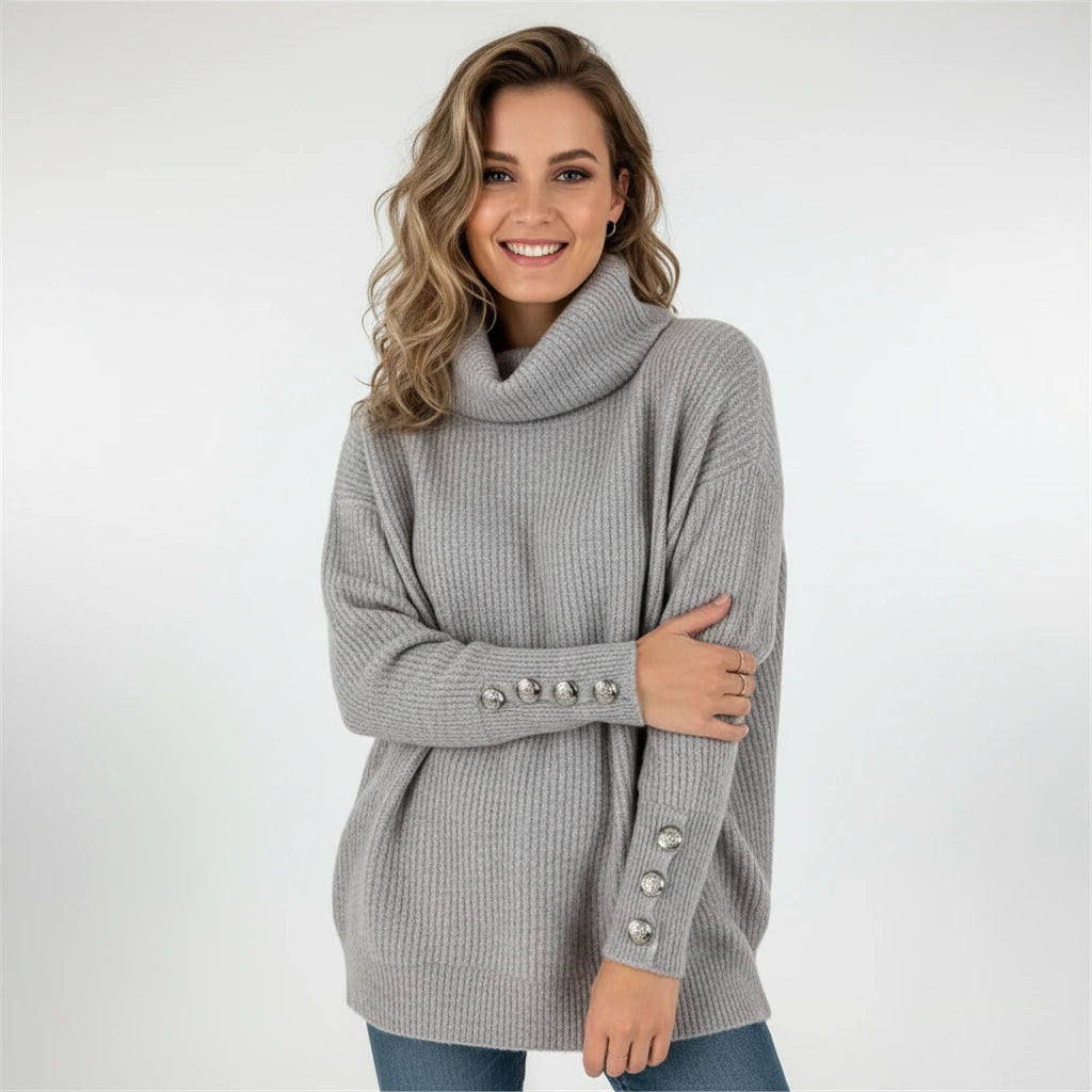 Woman wearing grey ribbed cowl neck sweater with button cuffs, studio photo