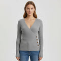 Woman wearing grey ribbed wrap sweater with side button detail, studio photo