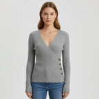 Woman wearing grey ribbed wrap sweater with side button detail, studio photo