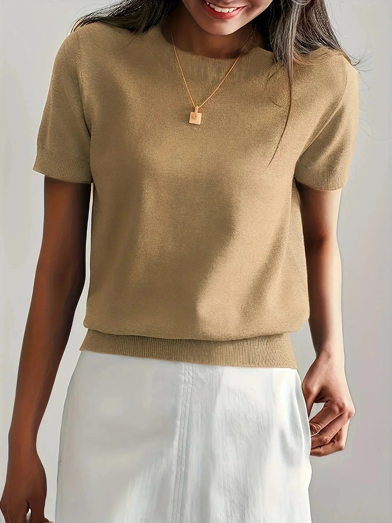 Woman wearing a khaki fine knit sweater with short sleeves, side view
