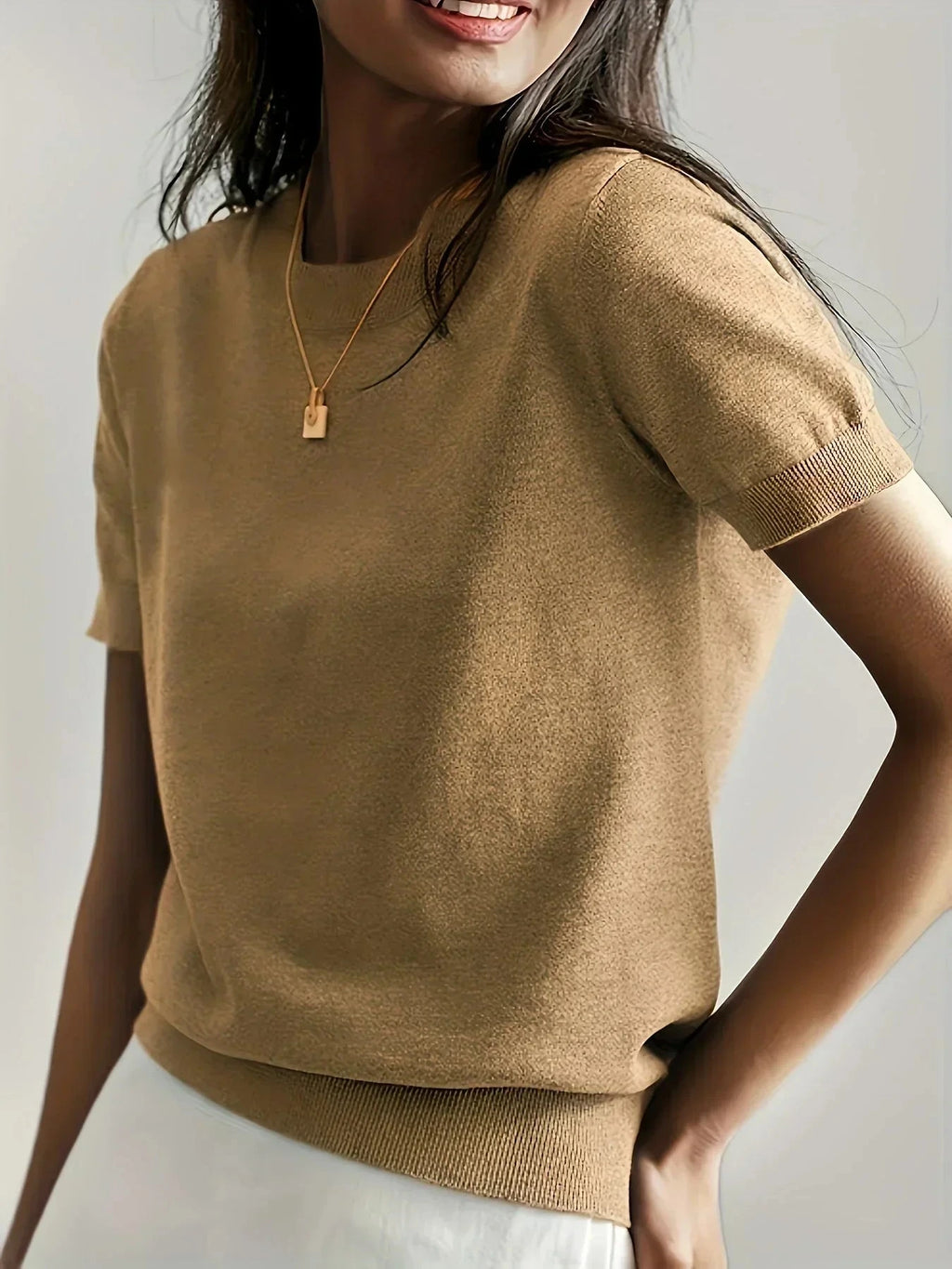 Woman wearing a khaki fine knit sweater with short sleeves and ribbed trim