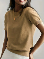 Woman wearing a khaki fine knit sweater with short sleeves and ribbed trim