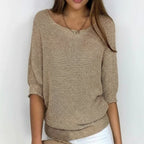 Woman wearing a khaki relaxed knit sweater with wide neckline and dolman sleeves, studio shot