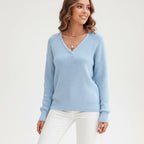 Woman wearing light blue ribbed V-neck sweater, studio photo