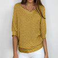 Woman wearing a mustard yellow relaxed knit sweater with wide neckline and dolman sleeves, studio shot