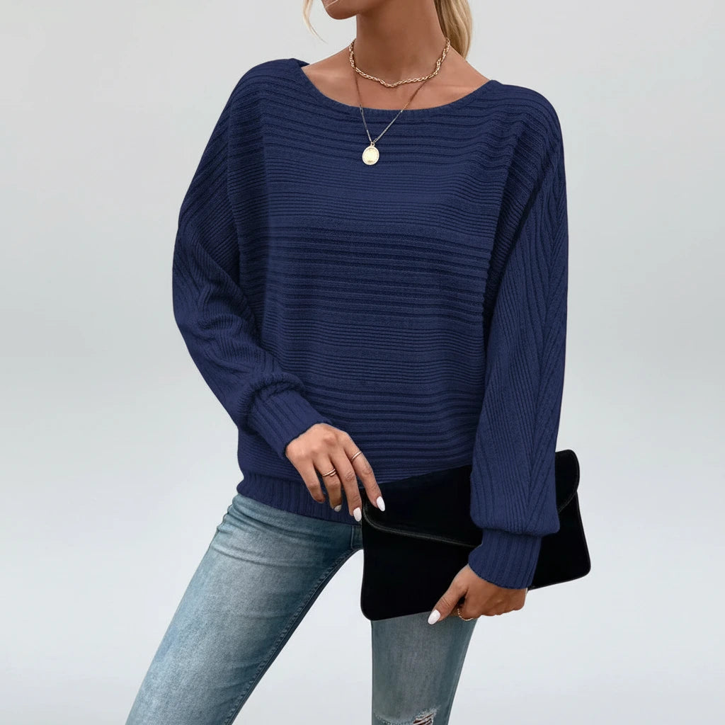 Woman wearing navy blue textured knit sweater with batwing sleeves, studio photo