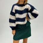 Woman wearing a navy blue striped chunky knit sweater, alternate studio angle