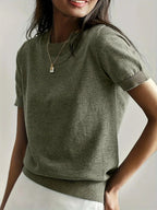 Woman wearing an olive green fine knit sweater with short sleeves and ribbed trim
