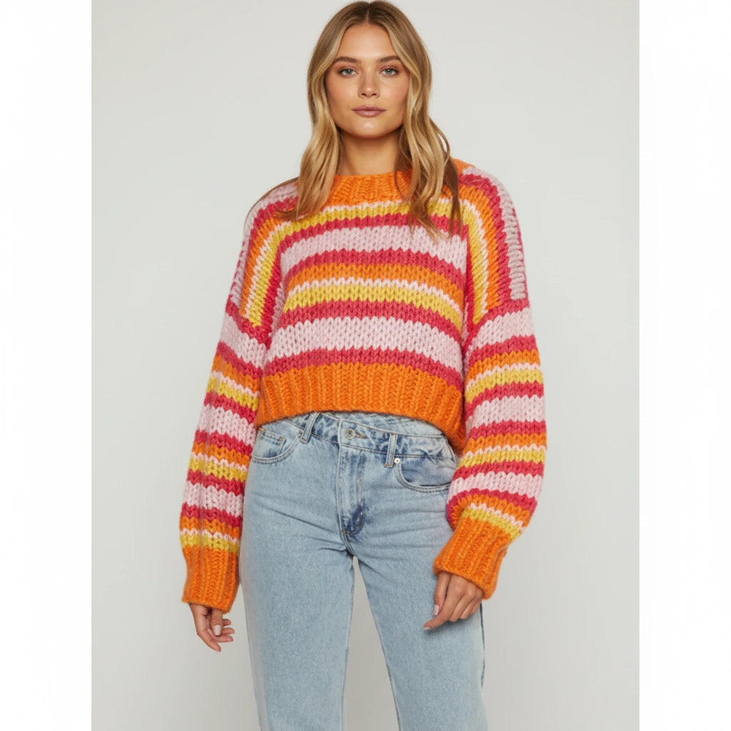 Woman wearing an orange striped chunky knit sweater with balloon sleeves, studio shot