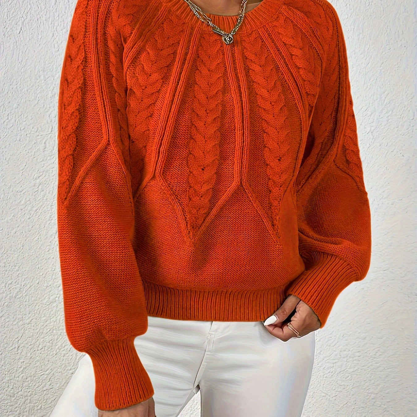 Woman wearing an orange voluminous sleeve sweater with cable knit texture