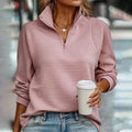 Woman wearing pink ribbed quarter-zip sweater with raised collar