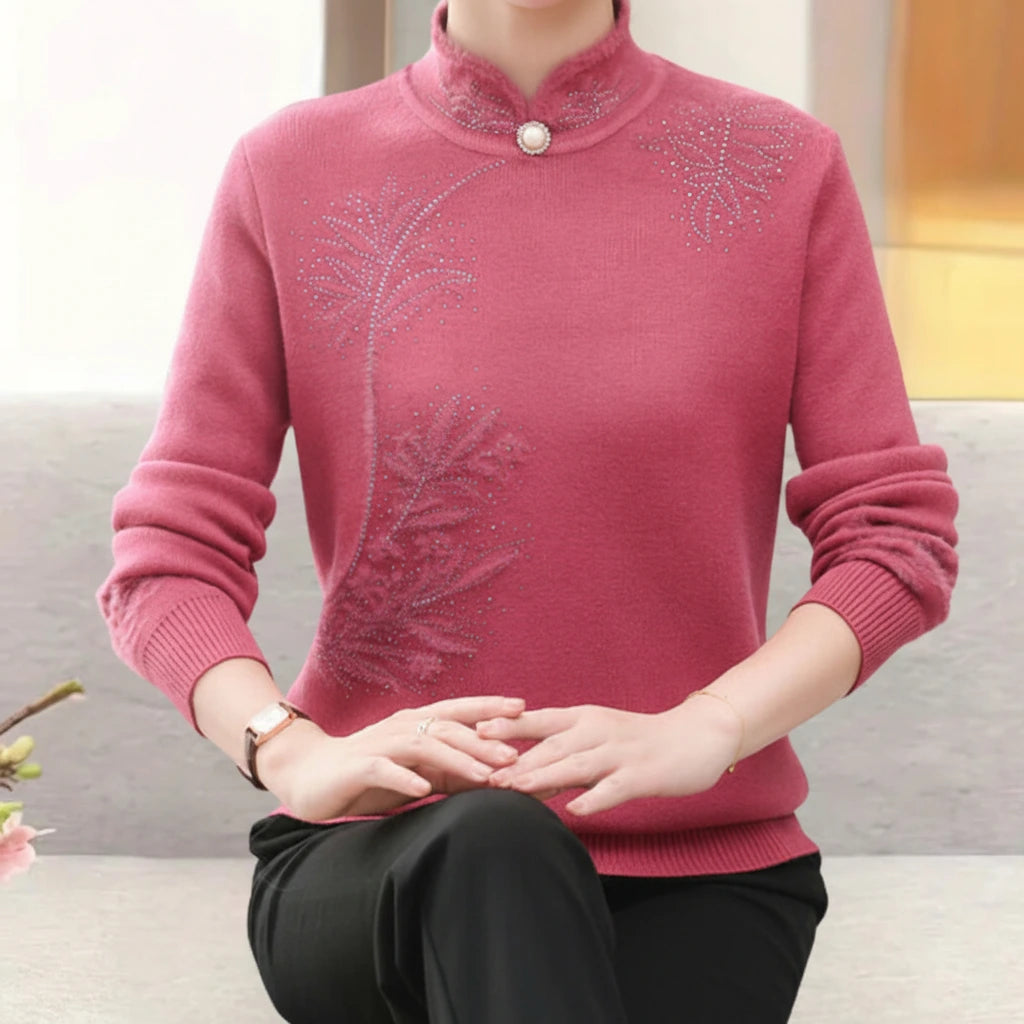 Woman wearing pink high-collar sweater with printed button detail, seated