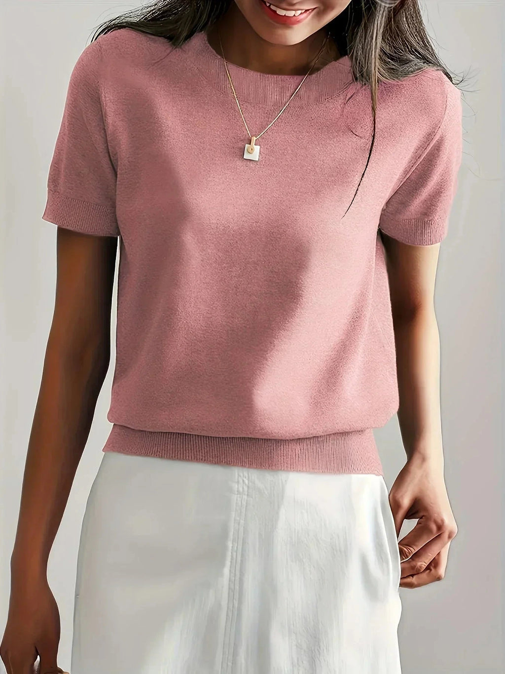 Woman wearing a pink fine knit sweater with short sleeves, side view