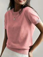 Woman wearing a pink fine knit sweater with short sleeves and ribbed trim