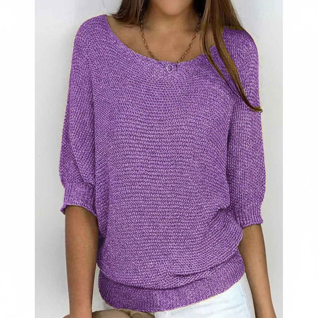 Woman wearing a purple relaxed knit sweater with wide neckline and dolman sleeves, studio shot