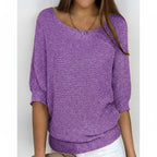 Woman wearing a purple relaxed knit sweater with wide neckline and dolman sleeves, studio shot