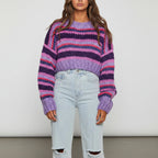 Woman wearing a purple striped chunky knit sweater with balloon sleeves, studio shot