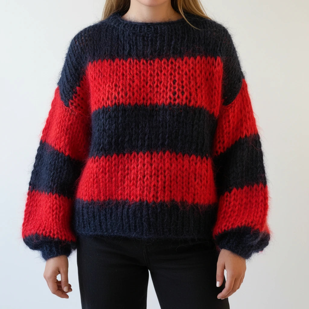 Woman wearing a red and black striped chunky knit sweater with balloon sleeves, studio shot