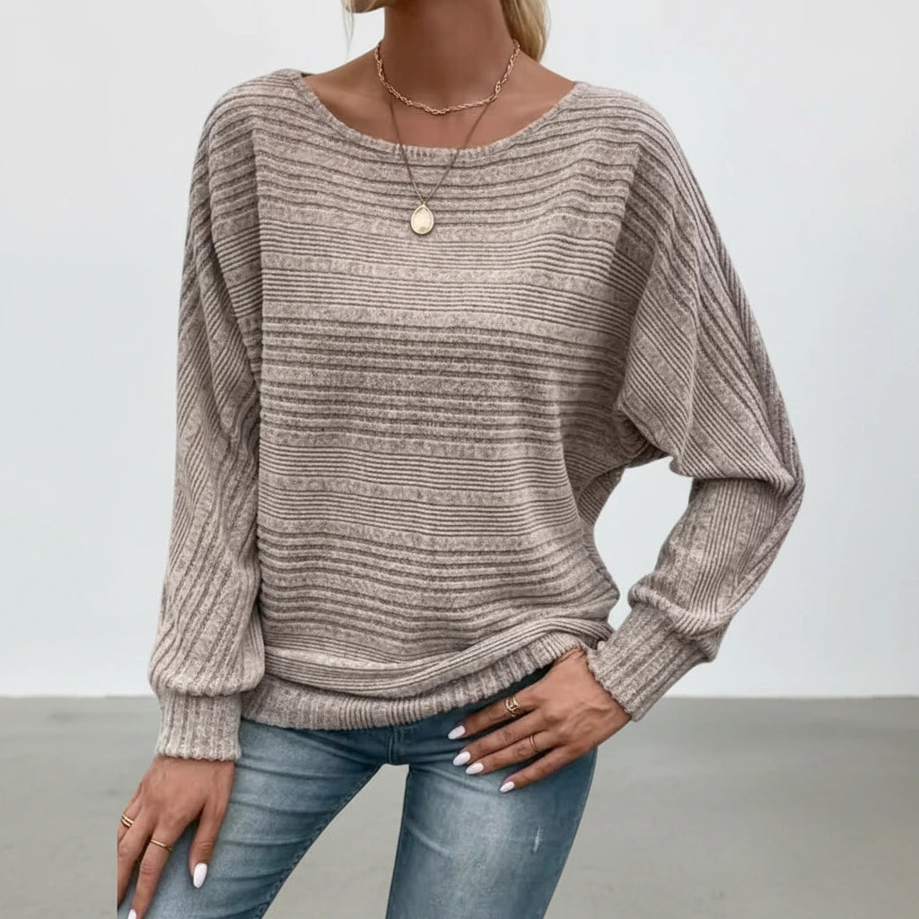 Woman wearing taupe textured knit sweater with batwing sleeves, studio photo