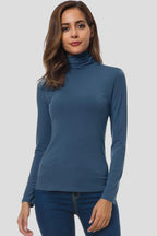 Woman wearing a blue turtleneck long sleeve plain sweater - studio photo