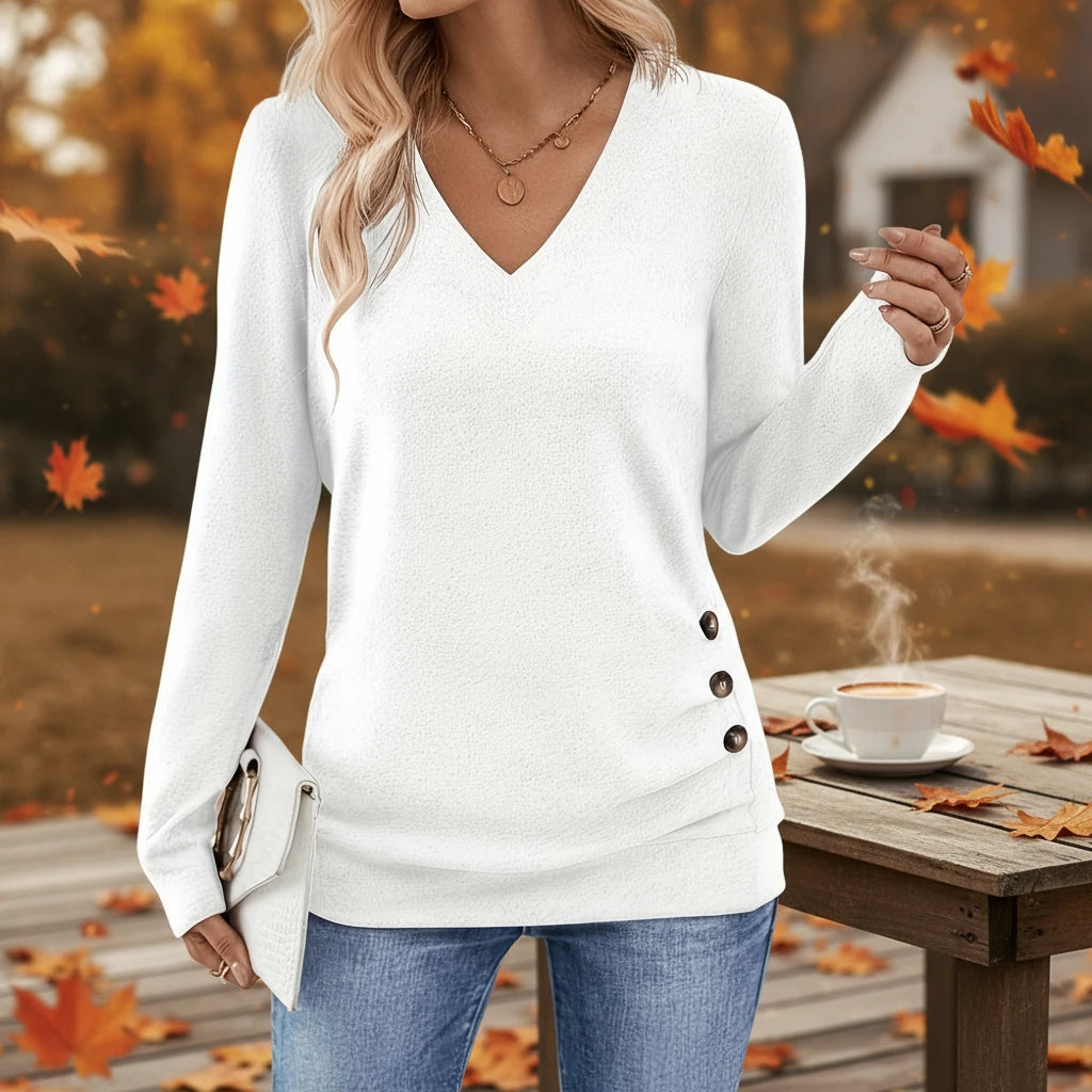 Woman wearing white V-neck sweater with side button detail outdoors in autumn
