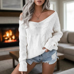 Woman wearing white oversized openwork sweater with cable texture by a fireplace