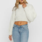 Woman wearing a white chunky knit sweater with balloon sleeves, studio shot