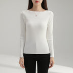 Woman wearing white ribbed boat neck sweater, studio photo