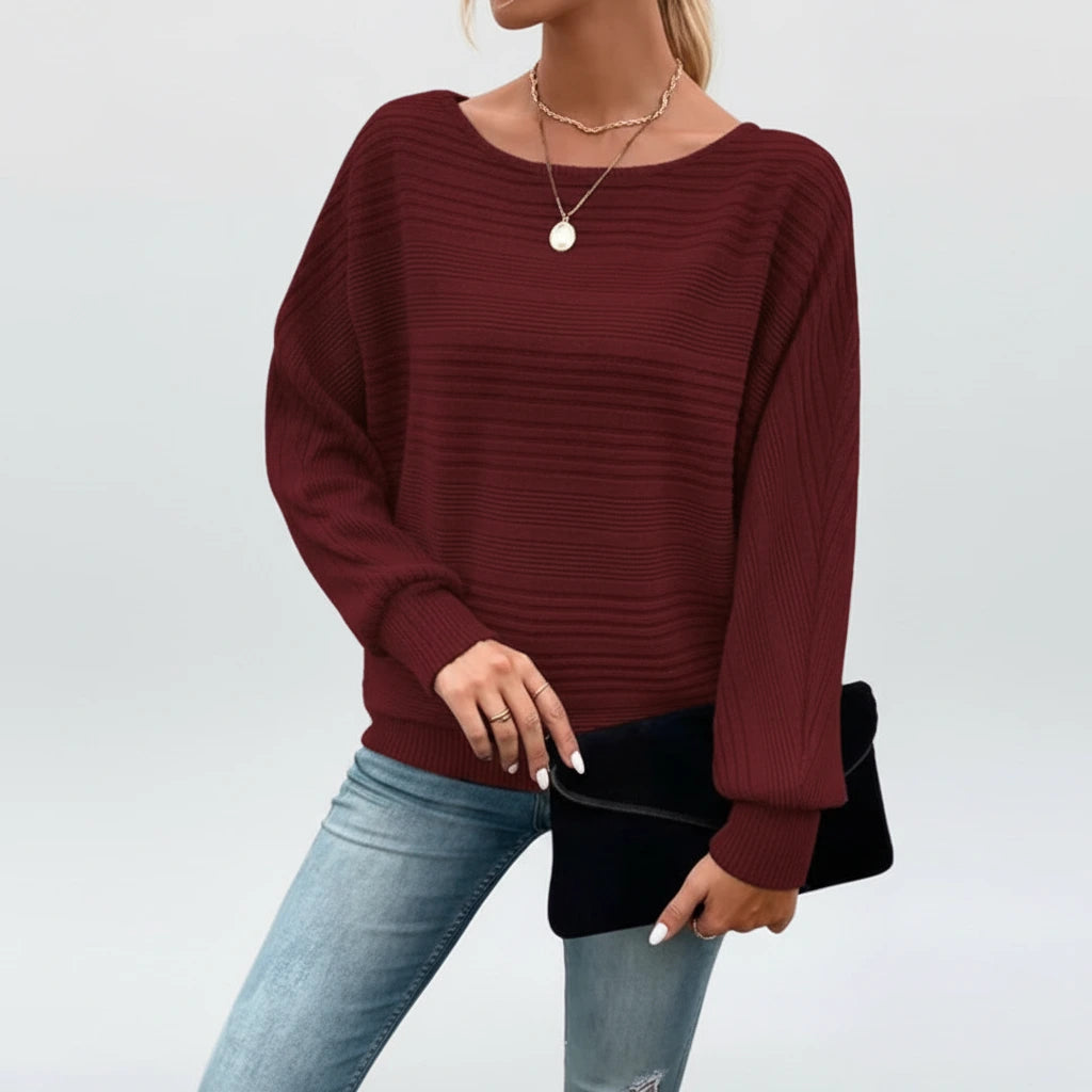 Woman wearing wine red textured knit sweater with batwing sleeves, studio photo