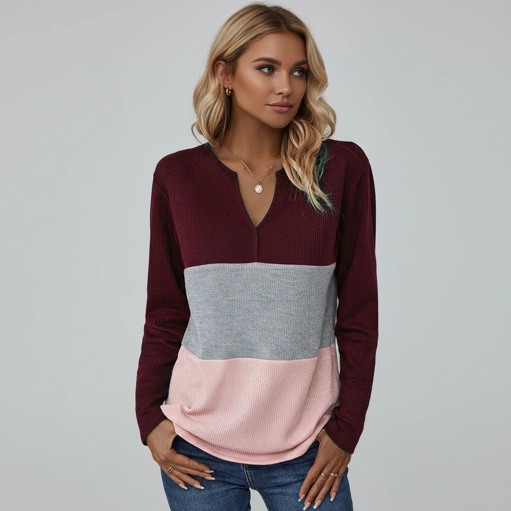 Woman wearing wine red panelled V-neck sweater, studio photo