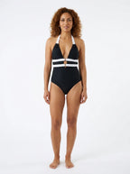Woman wearing a black and white striped plunge one-piece swimsuit, studio photography, front view
