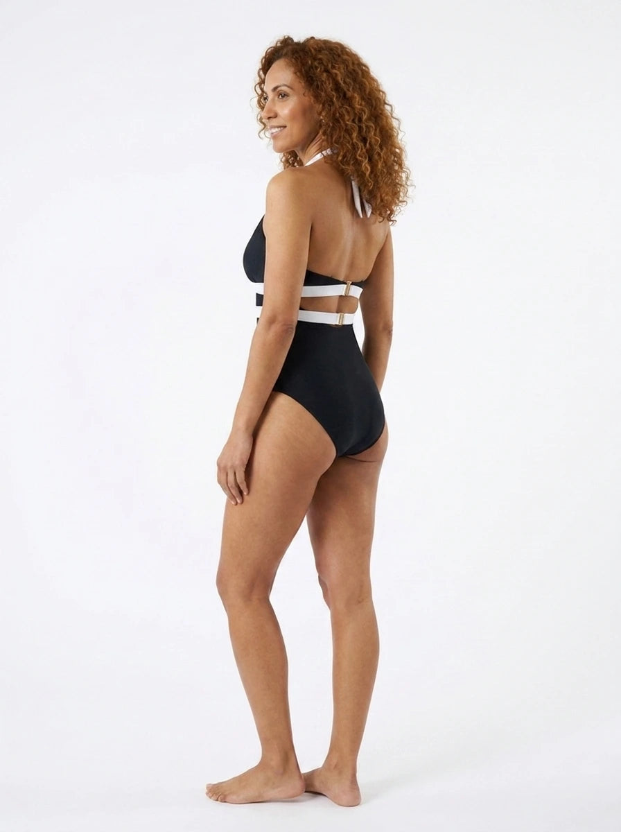 Woman wearing a black and white striped plunge one-piece swimsuit, studio photography, back view